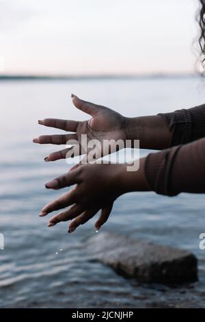 Kurze dunkle Haut Frau sanft berühren und spritzt frisches kühles blaues klares Wasser im Meer oder Fluss mit den Händen. Speicherplatz kopieren Stockfoto