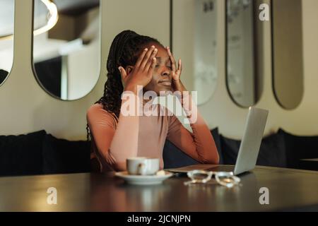 Erschöpft, wütend gemischte Rennen afro amerikanische Geschäftsfrau, Freiberufler arbeiten online sitzen mit Laptop im kreativen Büro Stockfoto