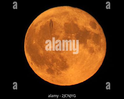 Sheerness, Kent, Großbritannien. 14.. Juni 2022. Wetter in Großbritannien: Ein Hochflugjet verlässt heute Abend eine Dampfspur, wenn er vor dem Super Strawbery Moon über Sheerness, Kent, vorbeifährt. Kredit: James Bell/Alamy Live Nachrichten Stockfoto