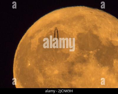 Sheerness, Kent, Großbritannien. 14.. Juni 2022. Wetter in Großbritannien: Ein Hochflugjet verlässt heute Abend eine Dampfspur, wenn er vor dem Super Strawbery Moon über Sheerness, Kent, vorbeifährt. Kredit: James Bell/Alamy Live Nachrichten Stockfoto