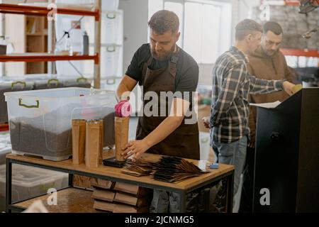 In der Kaffeefabrik wiegt der Geschäftsinhaber eine Papiertüte mit Kaffeebohnen auf einer Waage Stockfoto