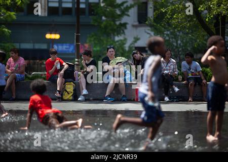 Chicago, USA. 14.. Juni 2022. Am 14. Juni 2022 sitzen Menschen im Schatten, während Kinder in der Innenstadt von Chicago, den Vereinigten Staaten, mit Wasser spielen. Die Metropolregion Chicago ist auf eine Hitzewelle in der Schwebe, da der US-Wetterdienst am Montag eine Wärmeempfehlung für die Region herausgab. Kredit: Vincent D. Johnson/Xinhua/Alamy Live Nachrichten Stockfoto