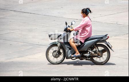 SAMUT PRAKAN, THAILAND, APR 02 2022, Eine Frau mit Gesichtsmaske fährt ein Motorrad Stockfoto