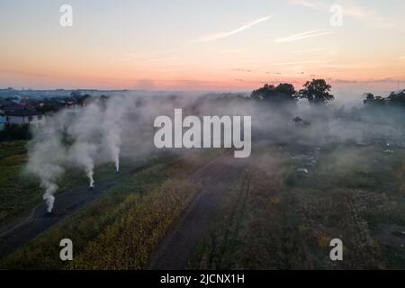 Luftaufnahme von Lagerfeuern von landwirtschaftlichen Abfällen durch trockenes Gras und Strohstoppel, die während der Trockenzeit auf Ackerland mit dichtem Rauch die Luft verschmutzen Stockfoto