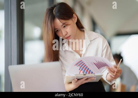 Steuerkonzept für Wirtschaftsprüfung. Porträt einer glücklichen asiatischen Geschäftsfrau, die im Büro arbeitet. Stockfoto