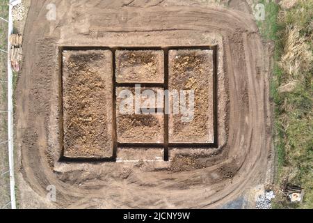 Ausgegraben Graben für die Bauarbeiten des neuen Hausbetonfundaments auf der Baustelle Stockfoto