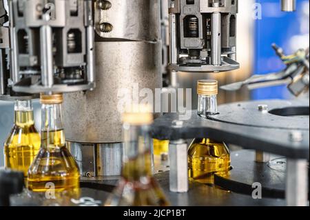 Die automatische Ausrüstung bringt Verschlüsse auf Flaschen mit alkoholischen Getränken Stockfoto