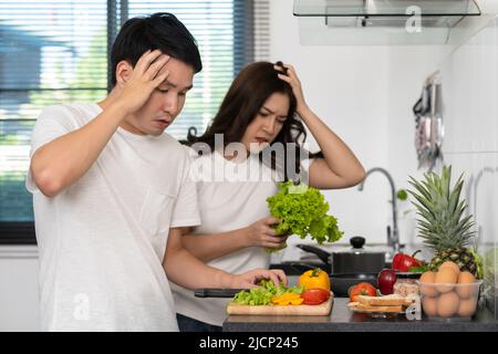 Müdes Paar kocht und bereitet Gemüse in der Küche zu Hause zu Stockfoto