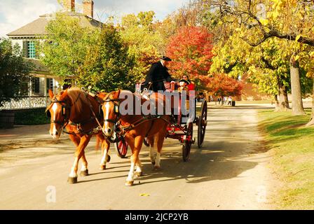 Eine Pferdekutsche führt die Besucher im Herbst auf eine entspannende Tour durch die historischen Gebäude und Häuser von Colonial Williamsburg in Virginia Stockfoto