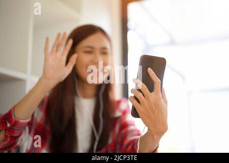 Focus Hand Bild, Eine hübsche junge asiatische Frau live-Streaming auf ihren sozialen Medien oder Videoanruf mit ihren Freunden über das Smartphone im Haus. Stockfoto