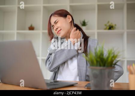 Office-Syndrom-Konzept, Millennial asiatische Geschäftsfrau mit Schulterschmerzen, leiden an Office-Syndrom. Stockfoto