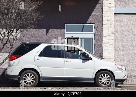 Ein Mitarbeiter, der einem Kunden seine Bestellung in einem McDonald's-Restaurant im Drive-Thru übergibt Stockfoto