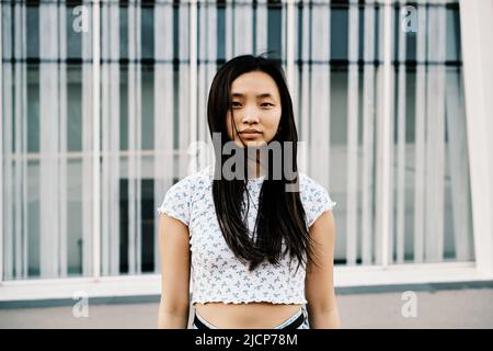 Porträt einer jungen asiatischen Frau, die im Freien auf die Kamera schaut. Stockfoto