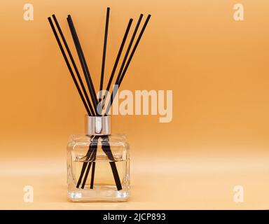 Lufterfrischer klebt isoliert auf beigem Hintergrund. Duftstäbchen und Flasche mit ätherischem Öl zur Entspannung Stockfoto