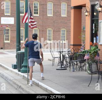 Der junge Gen Z-Mann (Generation Z) posiert mit seinem Handy für ein zeitgesteuertes Foto Stockfoto