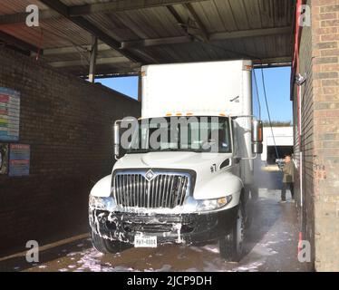 Mann wäscht einen weißen Lieferwagen bei einer LKW-Waschanlage in Irving, TX Stockfoto