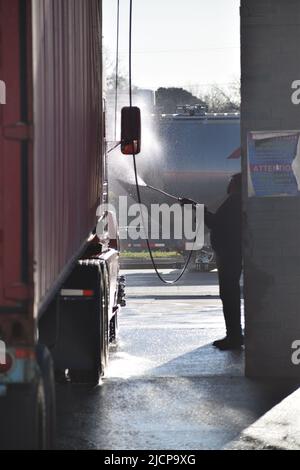 LKW-Fahrer wäscht seinen LKW an einer münzbetriebenen LKW-Waschanlage Stockfoto