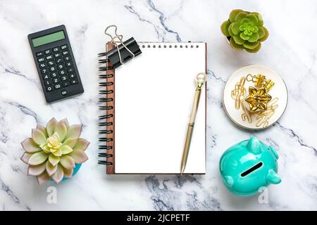 Notizblock, Sparschwein, Heimwerk, Rechner, Stift auf Marmorhintergrund Finanzplanung, Ziele, Projekt für Neujahr Konzept Draufsicht Flat Lay Finance Training und Strategien Copy space. Stockfoto