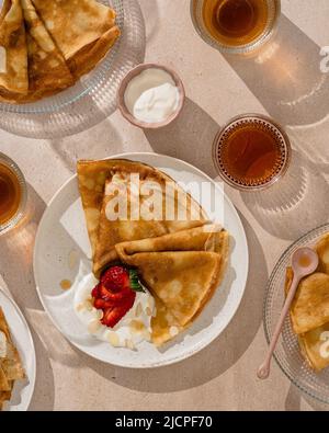 Pfannkuchen mit Erdbeeren und Joghurt, weißer Hintergrund, Ansicht von oben. Frühstück Konzept. Stockfoto