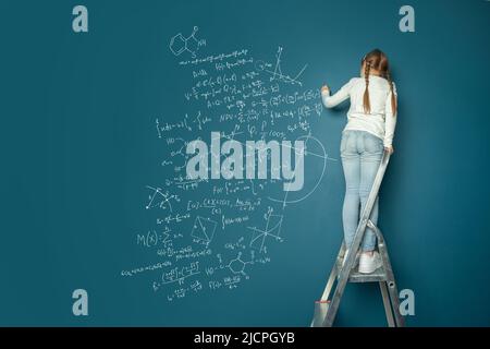 Kleines Kind Mathematik Student schreiben Wissenschaft Formeln auf blauem Hintergrund Stockfoto