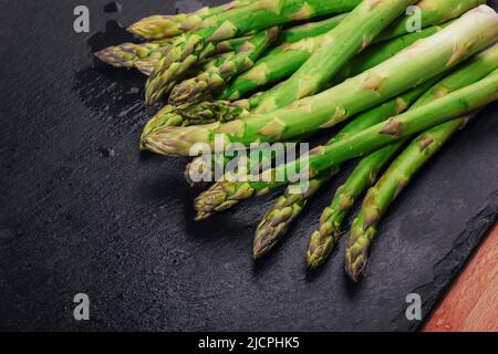 Frischer grüner Spargel auf schwarzem Schiefertafel, Nahaufnahme. Stockfoto