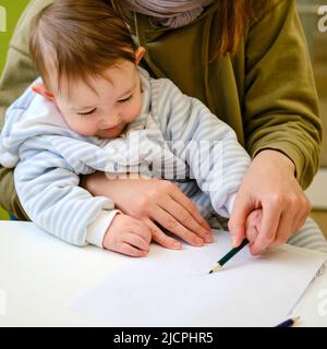 Eine Mutter mit einem Kleinkind-Baby zieht, während sie während eines Besuchs in einer Kinderklinik auf einen Arzt wartet. Ein Jahr altes Kind Stockfoto