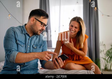 Junges Paar mit Smartphone mit Streit und Ehekonflikt wegen Betrug Stockfoto