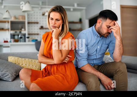 Traurige, nachdenkliche Paare, die an Beziehungsprobleme denken, die auf dem Sofa sitzen, Konflikte in der Ehe. Stockfoto