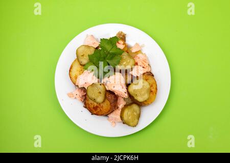 Frisch gebackener Lachs mit gebratener Kartoffel und Gurke auf dem Teller Stockfoto