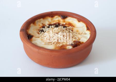 Profilansicht von schmackhaftem gebackenem Reispudding mit Haselnüssen auf, traditionelles Dessert, bekannt als in türkischem 'Sutlac' in Steingutkasserolle, geringe Tiefe Stockfoto