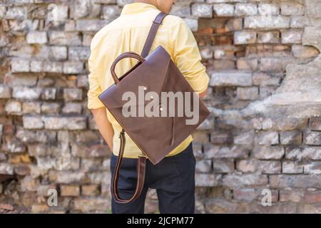 Rückseite des Mannes mit braunem Lederrucksack. Unisex-Tasche zum Verkauf. Rucksack ohne Markenaufdruck. Stockfoto