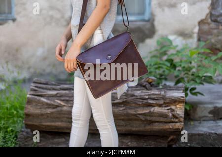 Frau mit brauner Ledertasche in der Hand. Unisex-Tasche Stockfoto