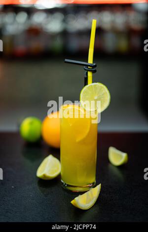 Ein Glas Limonade aus frischem Obst an der Theke mit Zitrus- und Beerenlimonade und Eiswürfeln Stockfoto