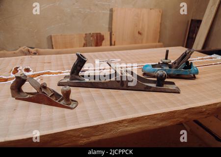 Alte Jointer-Ebenen liegen auf Holztisch. Holzbearbeitungswerkzeuge auf Holztisch. Schreinerei Stockfoto