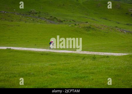 Oldtimer-Radfahrer, die auf der Schotterpiste zum Hoad-Denkmal beim Veloretro-Radrennen in Ulverston, Cumbria, Großbritannien, fahren. Stockfoto