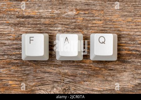Vier Computertastaturtasten angeordnet, um FAQ-Wort auf dem hölzernen Hintergrund zu buchstabieren Stockfoto