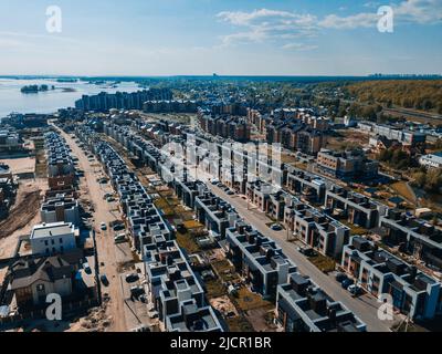 Luftpanorama-Ansicht des Wohnstadtbereichs des schönen Vororts des Wohnhauses in der Nähe des Flusses aus einer Höhe. Neue Stadthaus-Gemeinschaft. Häuser und private Höfe. Blick auf Stadthäuser von der Drohne. Stockfoto