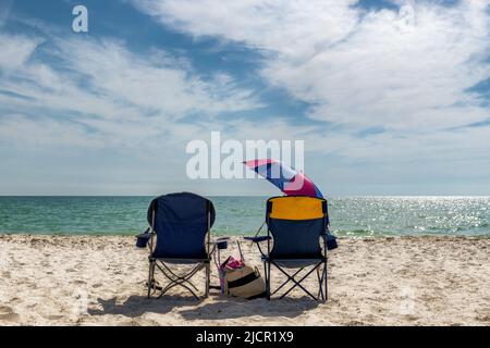 Sonnenuntergangsansicht von Liegestühlen mit Strandzubehör in Naples Beach, Florida, USA Stockfoto