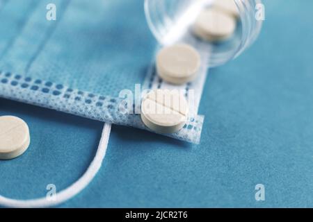 Medizinische Maske, Tabletten und Fläschchen mit Medikamenten auf der blauen Oberfläche. Coronavirus, Grippe, Konzept für Atemwegserkrankungen. Horizontale Ausrichtung. Draufsicht. Stockfoto