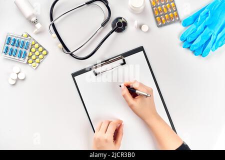 Die Hand der Ärztin füllt die Krankenakte auf dem weißen Tisch Stockfoto