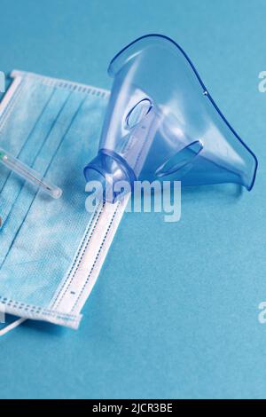 Medizinische Maske, Spritze und Tabletten schließen sich auf dem blauen Hintergrund. Coronavirus, Grippe, Konzept für Atemwegserkrankungen. Horizontale Ausrichtung. Draufsicht. Stockfoto