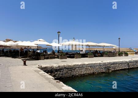 Touristen essen in einem Restaurant an der alten Hafenmauer in Chanie, Kreta Stockfoto