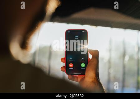 Person, die unter seinen Telefonkontakten nach einer Nummer sucht. Anrufende Clients. Junger Mann, der eine Nummer auf seinem Handy registriert Stockfoto