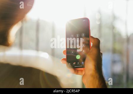 Person, die unter seinen Telefonkontakten nach einer Nummer sucht. Anrufende Clients. Junger Mann, der eine Nummer auf seinem Handy registriert Stockfoto