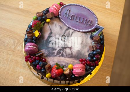 Ein Kuchen zum Kindergeburtstag mit Beeren, Früchten, Makronen, die ein süßes persisches Kätzchen darstellen Stockfoto