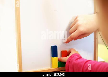 Kinder spielen magnetische Holzspiel. Kinder spielen mit einem Spielzeug auf weißem Hintergrund. Kinder spielen mit einem Konstrukteur Stockfoto