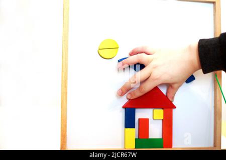 Kind spielt hölzerne magnetische Lernspiel. Mädchen spielt mit einem Spielzeug auf weißem Hintergrund. Stockfoto