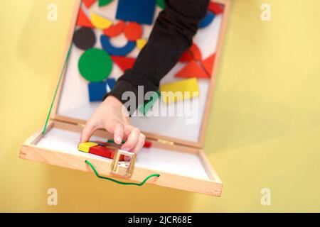 Kind spielt hölzerne magnetische pädagogische Spiele. Kinder spielen Mosaik. Blick von oben. Kind spielt mit einem Konstrukteur Stockfoto