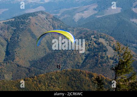 Gleitschirm fliegt am blauen Himmel mit Berg im Hintergrund. Stockfoto