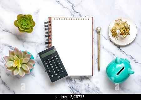 Notizblock, Sparschwein, Heimwerk, Rechner, Stift auf Marmorhintergrund Finanzplanung, Ziele, Projekt für Neujahr Konzept Draufsicht Flat Lay Finance Training und Strategien Copy space. Stockfoto